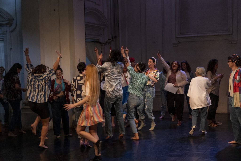 Group of boys and girls participating in Creativa during a show, wearing very colorful clothes, while they jump and rejoice.