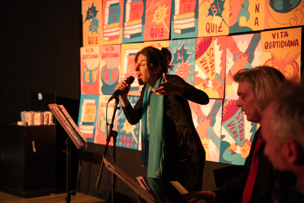 Una cantante si esibisce insieme ai musicisti durante lo spettacolo. Dietro di loro le caselle del gioco