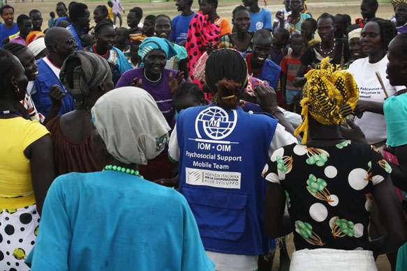 Group of South Sudanese people in a street during an event. In the middle is an operator from the IOM Psychosocial Support Mobile Team.