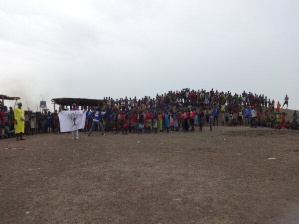 Wide-angle shot of the audience during an outdoor event in South Sudan, all standing on a small hill.