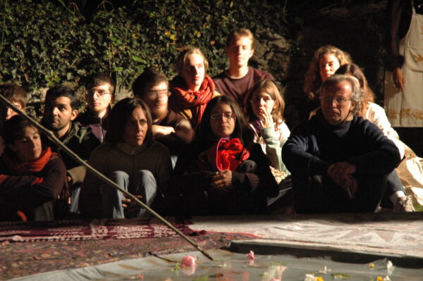 Audience watching the show, in the evening, sitting on the ground
